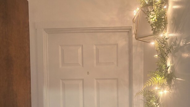 A white door with a keyhole and a doorknob, a wooden door frame to the left, and a string of lights on the wall to the right. - Quiet central studio apartment in the Capital Hill neighborhood of Denver (Denver)