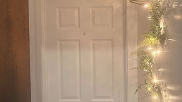 A white door with a keyhole and a doorknob, a wooden door frame to the left, and a string of lights on the wall to the right.