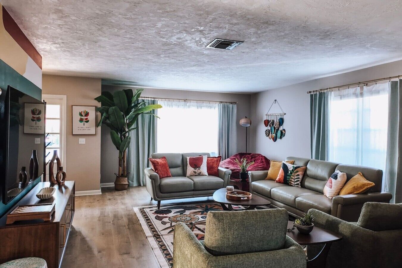 A living room with a sofa set, a coffee table, a television, and a large plant.