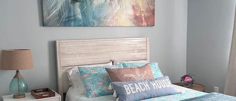 Une chambre à coucher comprenant un lit, une table de chevet, une lampe, un ventilateur de plafond et un climatiseur fixé au mur.