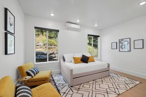 A modern bedroom with a bed, two windows, a sofa, and a rug.