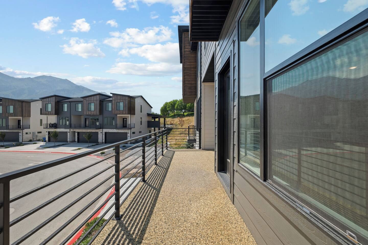 Un edificio moderno con ventanas amplias y un balcón con vista a un estacionamiento.