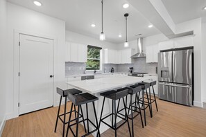 Eine moderne Küche mit weißen Schränken, einem Edelstahl-Kühlschrank und Barhocker.