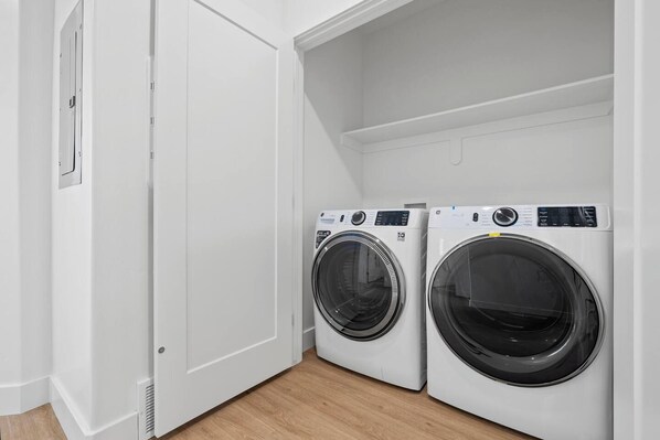 A laundry room with two front-loading washing machines and a white door.