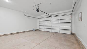 A clean, empty garage with a white door and a ceiling-mounted projector.