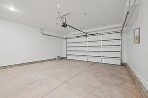 A clean, empty garage with a white door and a ceiling-mounted projector.