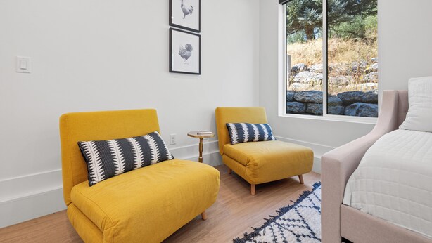 A modern bedroom with a large window, two yellow armchairs, a white bed, and two framed pictures on the wall. - Mountain Escape - Minutes to Snowbasin & Pineview - Sleeps 8 (Mountain Green)