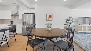 A modern kitchen with a dining area, featuring a round wooden table, metal chairs, and a built-in oven. - Mountain Escape - Minutes to Snowbasin & Pineview - Sleeps 8 (Mountain Green)
