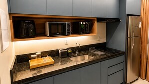 A modern kitchen with dark cabinetry, a stainless steel refrigerator, and built-in appliances. - Apartment with furnished balcony | Gym | Swimming pool | Complete linens (Goiânia)