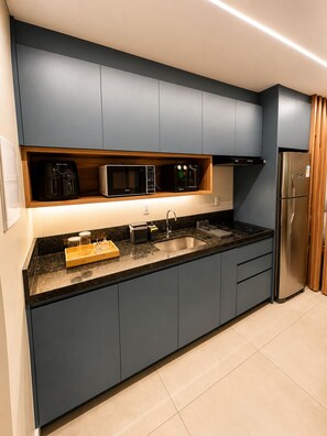 Eine moderne Küche mit dunklen Schränken, einem Edelstahlkühlschrank und integrierten Geräten.