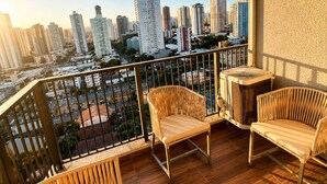 A balcony with wicker furniture and a city view. - Apartment with furnished balcony | Gym | Swimming pool | Complete linens (Goiânia)