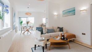 A modern living room with a sofa, coffee table, and dining area. - Broadstairs Duplex With Terrace Near Stone Bay FT1 (Broadstairs)