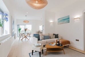 A modern living room with a sofa, coffee table, and dining area. - Broadstairs Duplex With Terrace Near Stone Bay FT1 (Broadstairs)