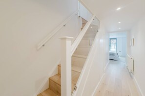 A staircase with white railings and wooden steps leading to a room with a bed and a window. - Broadstairs Duplex With Terrace Near Stone Bay FT1 (Broadstairs)
