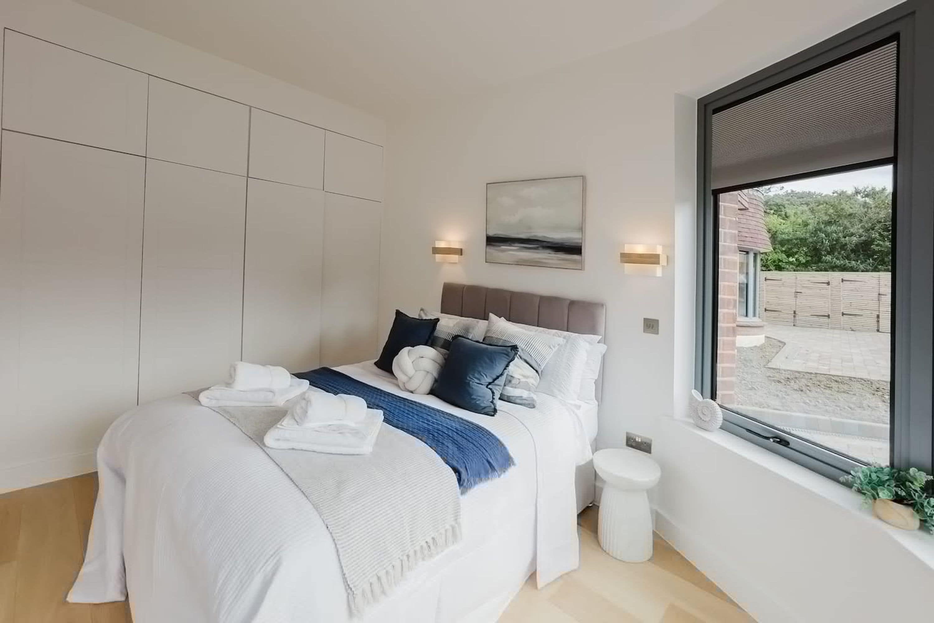 A modern bedroom with a large bed, a view of the outdoors, and built-in storage.
