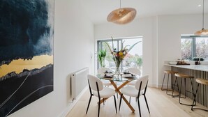 A modern dining area with a glass table, white chairs, and a hanging light fixture. - Broadstairs Duplex With Terrace Near Stone Bay FT1 (Broadstairs)