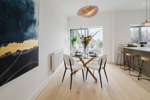 A modern dining area with a glass table, white chairs, and a hanging light fixture. - Broadstairs Duplex With Terrace Near Stone Bay FT1 (Broadstairs)