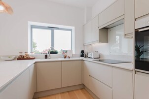 Una cocina moderna con armarios blancos, un ventanal y una encimera con diversos objetos.