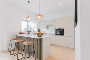 Een moderne keuken met een centraal eiland, barstoelen en een groot raam.