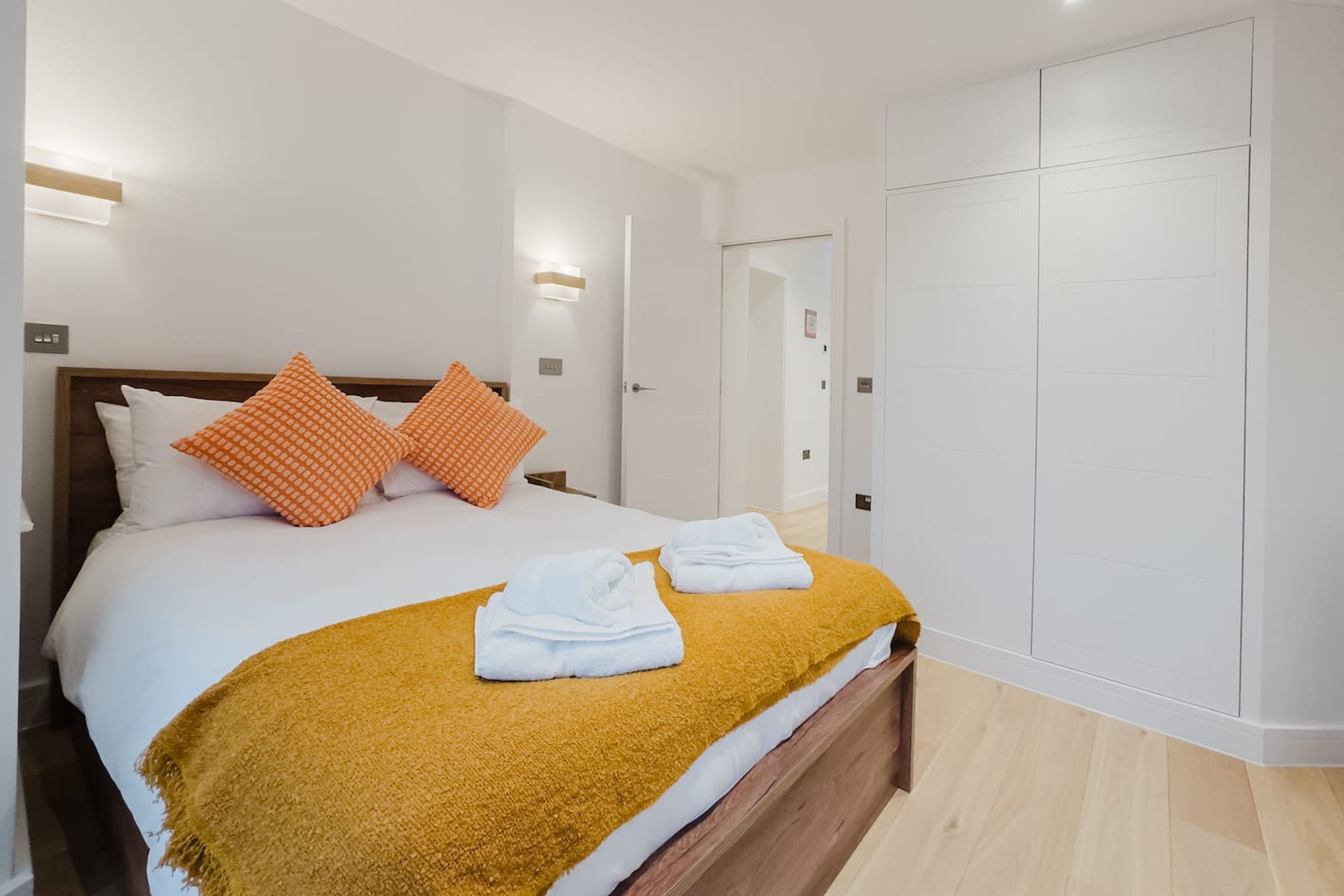 A hotel room with a bed, pillows, a blanket, and a wardrobe.
