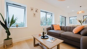 A modern living room with a sofa, a coffee table, and a potted plant. - Broadstairs 2 Bed Flat Balcony FT2 by Adliv (Broadstairs)