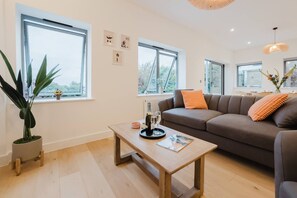 A modern living room with a sofa, a coffee table, and a potted plant. - Broadstairs 2 Bed Flat Balcony FT2 by Adliv (Broadstairs)
