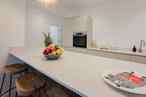 A modern kitchen with a marble countertop, a bowl of fruit, a toaster, and a refrigerator. - Broadstairs 2 Bed Flat Balcony FT2 by Adliv (Broadstairs)