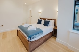 Un dormitorio moderno con una cama de madera, ropa de cama blanca y un plaid azul.