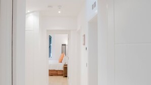 A hallway with a wooden floor leading to a bedroom with a bed and a nightstand. - Broadstairs 2 Bed Flat Balcony FT2 by Adliv (Broadstairs)