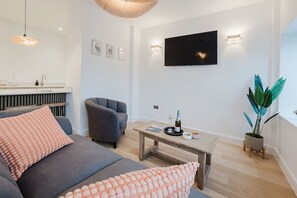 A modern living room with a sofa, armchair, coffee table, and a flat-screen TV mounted on the wall. - Broadstairs 2 Bed Flat Balcony FT2 by Adliv (Broadstairs)