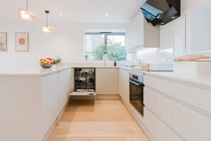Eine moderne Küche mit weißen Schränken, einem Geschirrspüler, einem Backofen und einem Fenster für natürliches Licht.