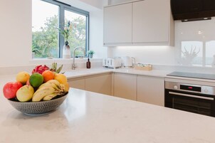 Una cocina moderna con un frutero sobre la encimera, una ventana con vistas a la vegetación y un horno empotrado.