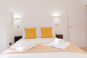 A hotel room with a bed, two bedside tables, and two wall-mounted light fixtures. - Seaview 2 Bed Retreat Balcony FT3 by Adliv (Broadstairs)