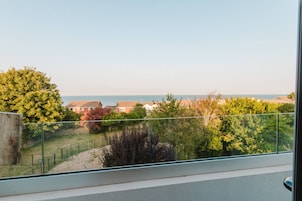 Varanda com vista para uma área residencial e o mar.
