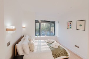 A bedroom with a bed, a window, and wall-mounted light fixtures.