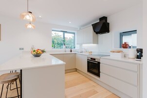 Una cocina moderna con una isla grande, muebles blancos y un horno empotrado.