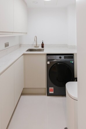 A compact laundry room with a washing machine, a sink, and a toilet. - Broadstairs Sea-view 2-balcony Flat FT4 by Adliv (Broadstairs)