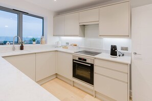 Eine moderne Küche mit Einbauofen, Kaffeemaschine und Fenster mit Blick auf eine Stadtlandschaft.