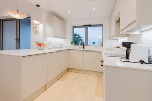 A modern kitchen with white cabinetry, a large island, and pendant lighting. - Broadstairs Sea-view 2-balcony Flat FT4 by Adliv (Broadstairs)