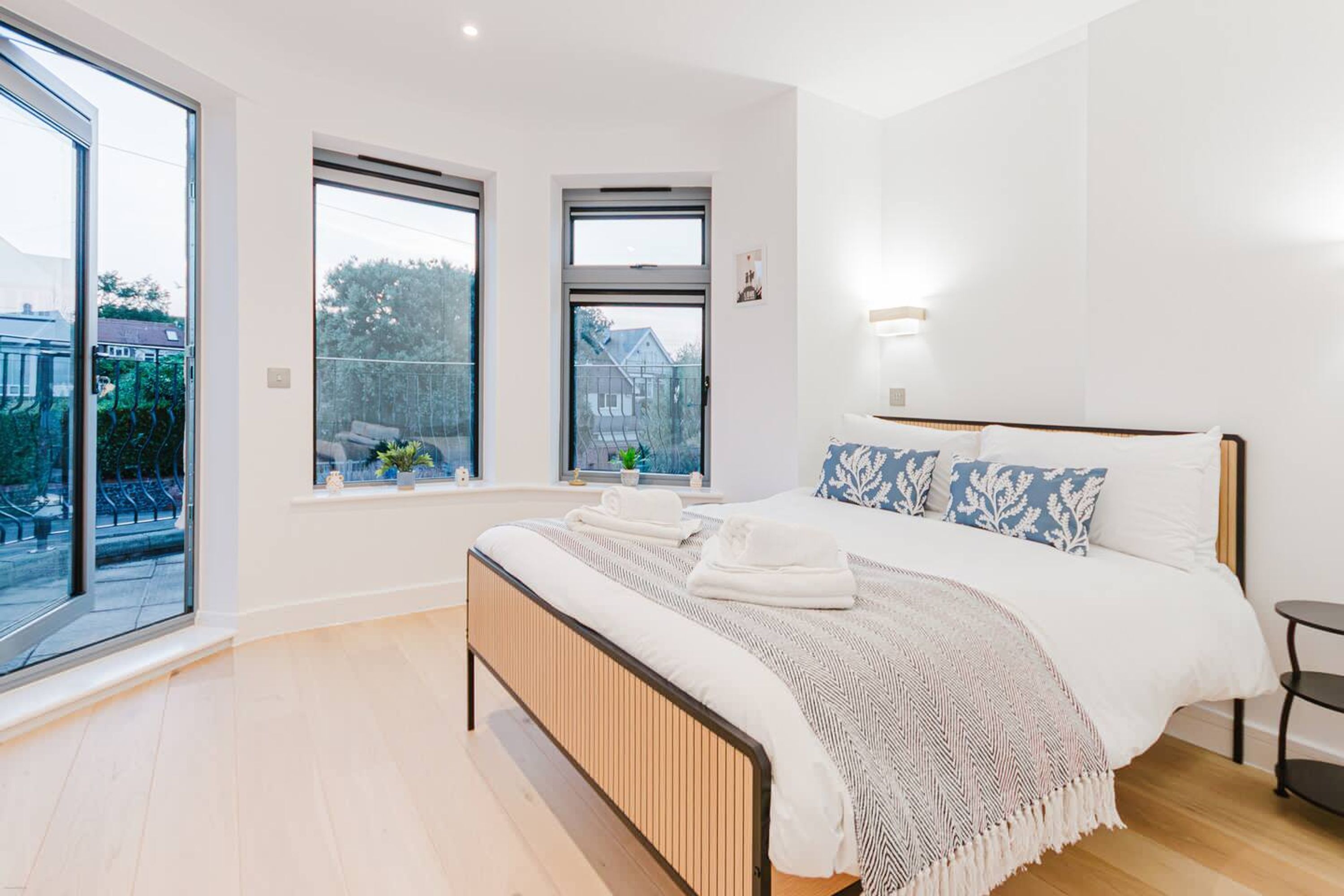 Un dormitorio moderno con una cama grande, dos ventanas y vistas al exterior.