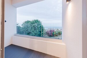 Un balcón con vistas a árboles y un paisaje lejano.