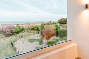 Ein Balkon mit Blick auf einen angelegten Garten und das Meer.