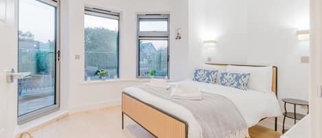 A modern bedroom with a large bed, two windows, and a view of the outside.