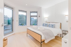 Quarto moderno com uma cama grande, duas janelas e vista para o exterior.