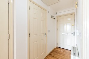 A hallway with white doors, wooden flooring, and a white ceiling. - Bright Stepney Green City Stay (London)