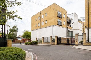 A multi-story residential building with a brick facade, a gated entrance, and a paved driveway. - Bright Stepney Green City Stay (London)