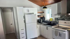 Una cocina moderna con armarios blancos, un refrigerador de acero inoxidable, un lavamanos doble y un horno empotrado.
