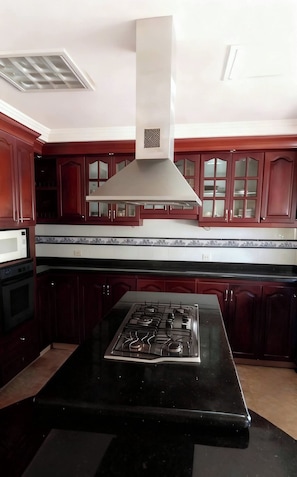 A kitchen with dark wooden cabinets, a stainless steel range hood, and a black countertop. - Ideal for a family getaway; pet-friendly 🌿 A rural retreat near Cali🏊 (Cali)