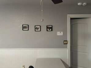 A room with a bed, a door, and three framed pictures on the wall.