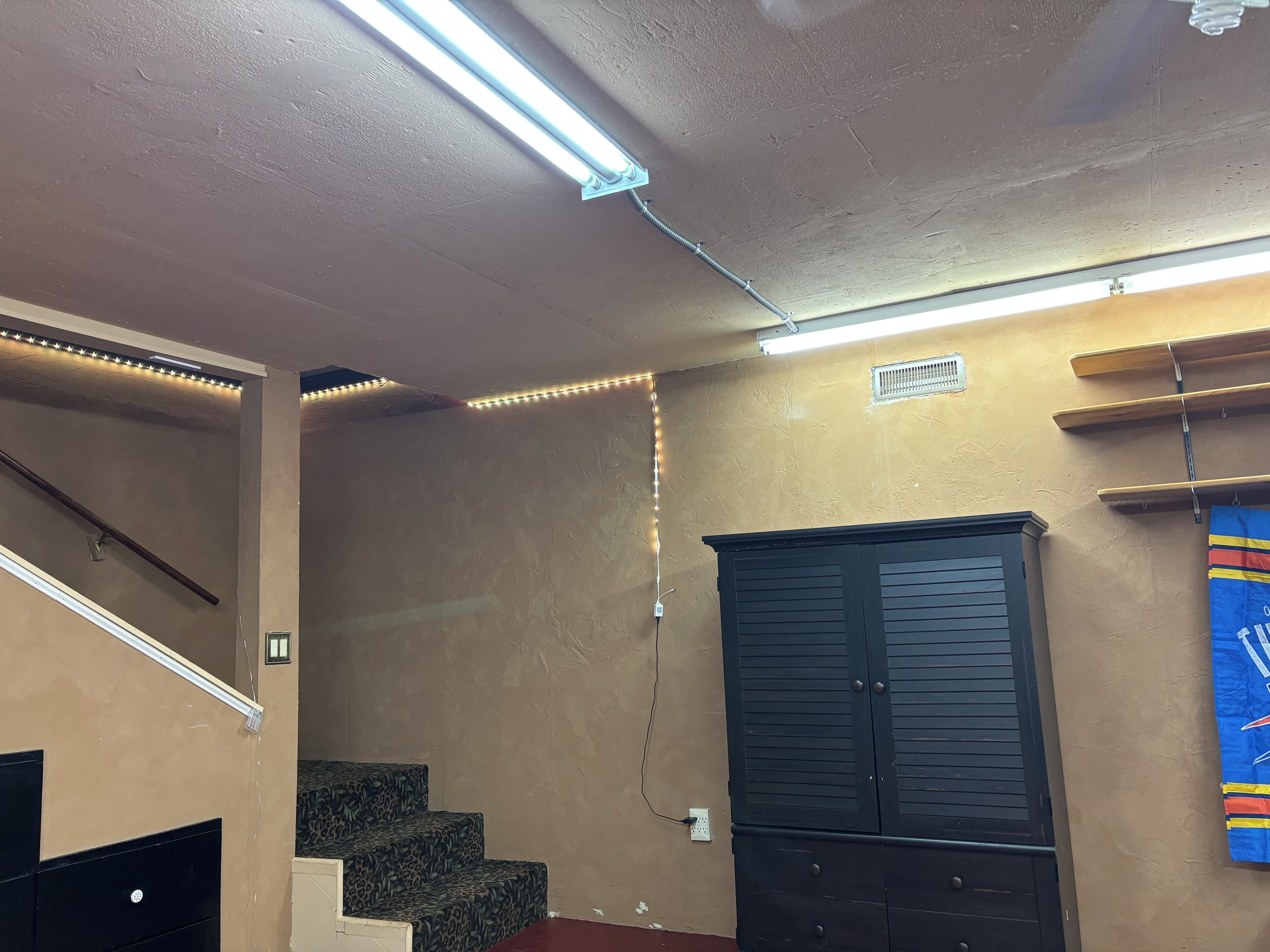 Une pièce avec un escalier, une armoire et une étagère fixée au mur.